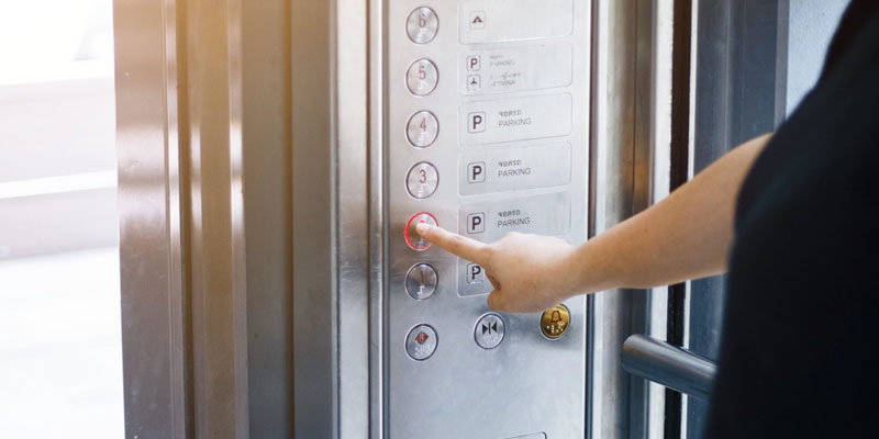 Women in an Elevator Pressing a Button